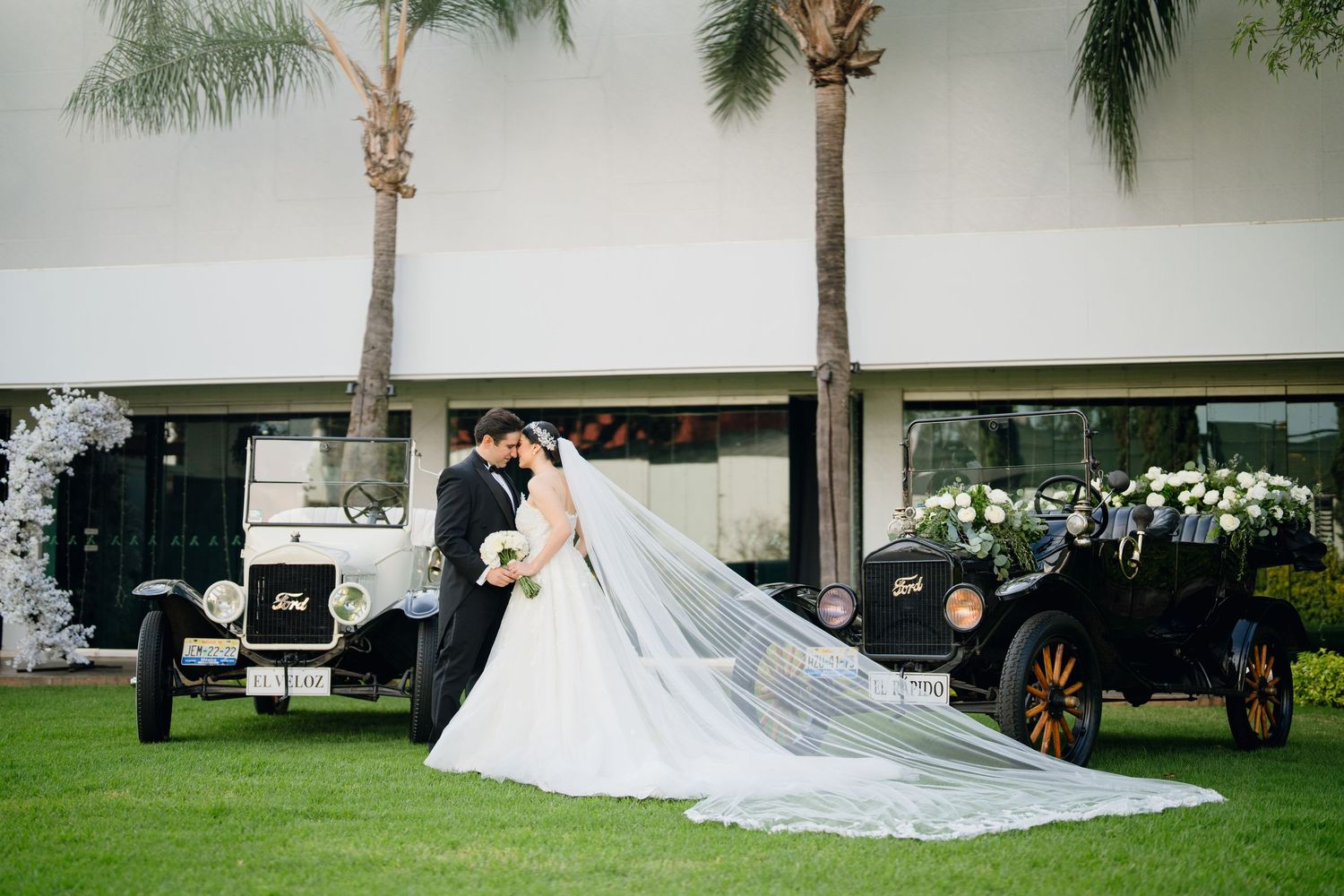 Elegant wedding ceremony setup with palm trees and white decor at an outdoor venue.