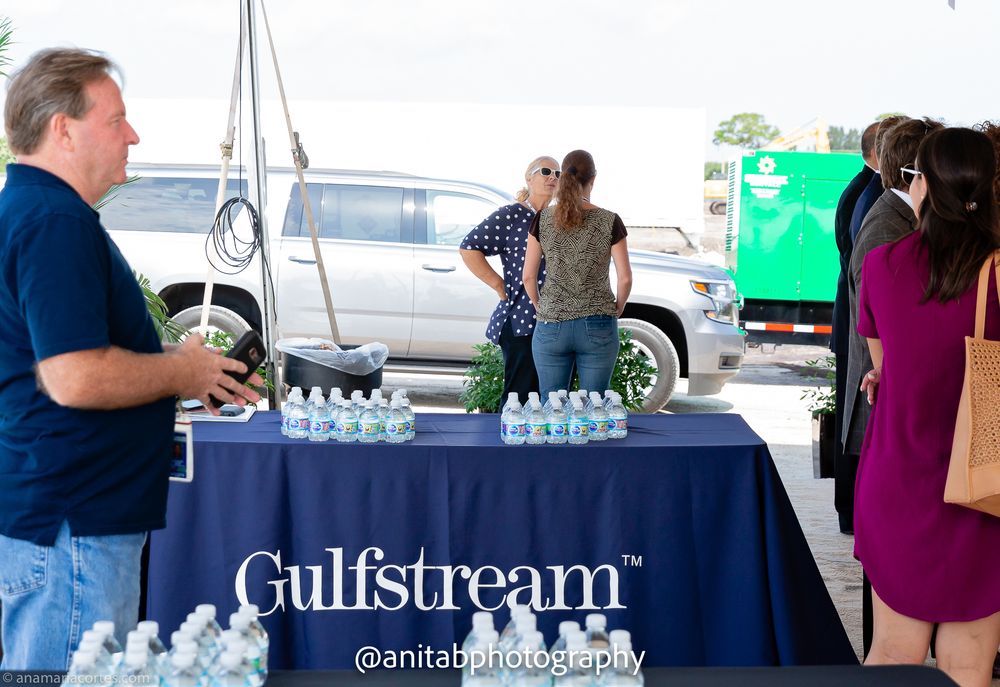 Business executives gather at a Gulfstream corporate event with display banners and refreshment tables.
Ground braking event.