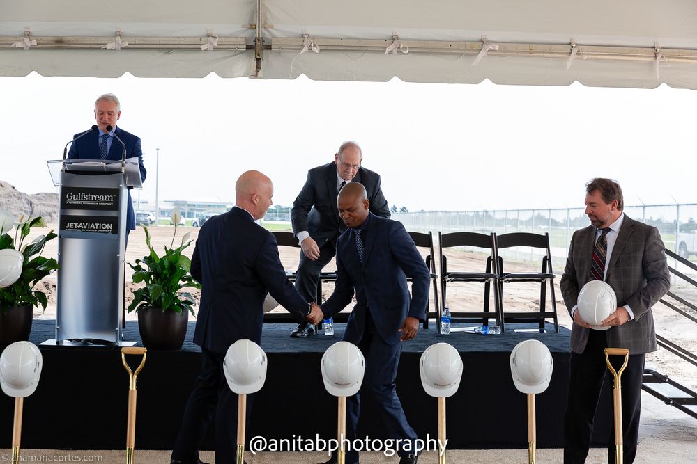Corporate executives seated in formal attire during groundbreaking ceremony with decorative white balloons.
Ground braking event.