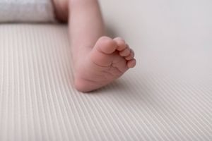 Close-up of a baby's tiny foot resting on textured white fabric.
