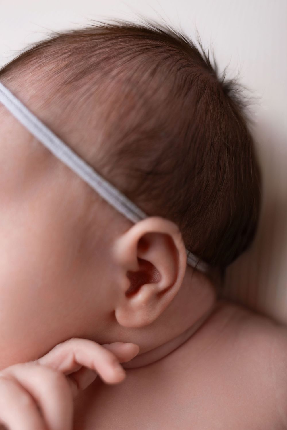 Close-up series showing a sleeping baby's head with a light-colored headband against a neutral background.