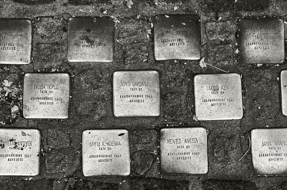 Stone markers or memorial plaques laid out in a grid pattern on a textured surface.