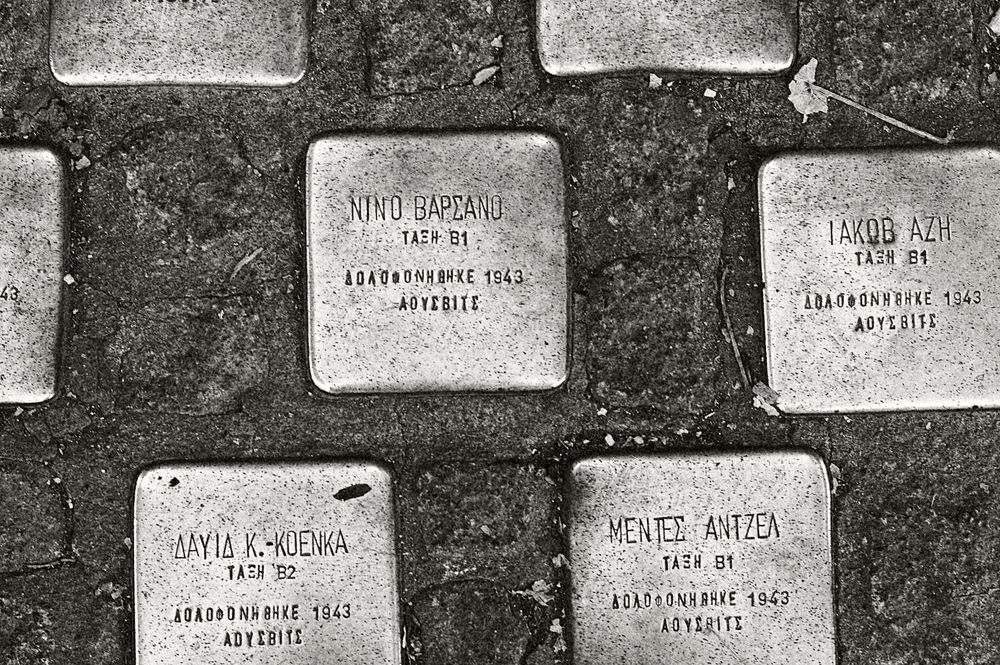 Multiple memorial stones or plaques arranged in rows against a dark background.