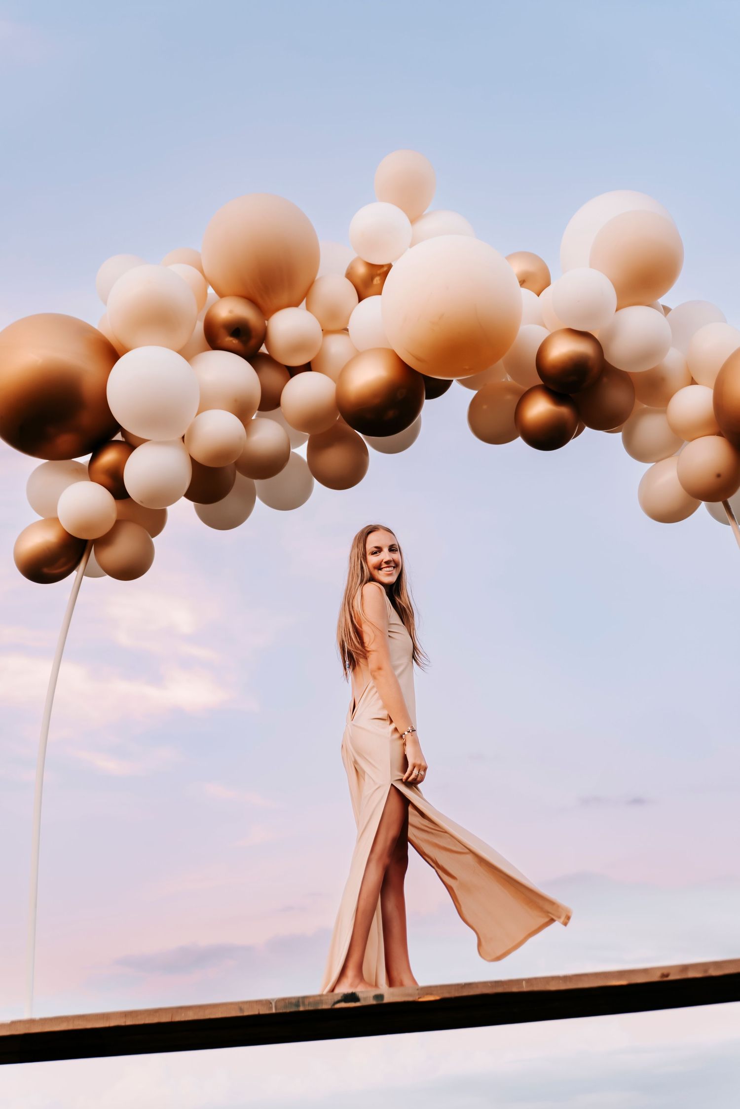 Girl standing on a board held by balloons in the sky