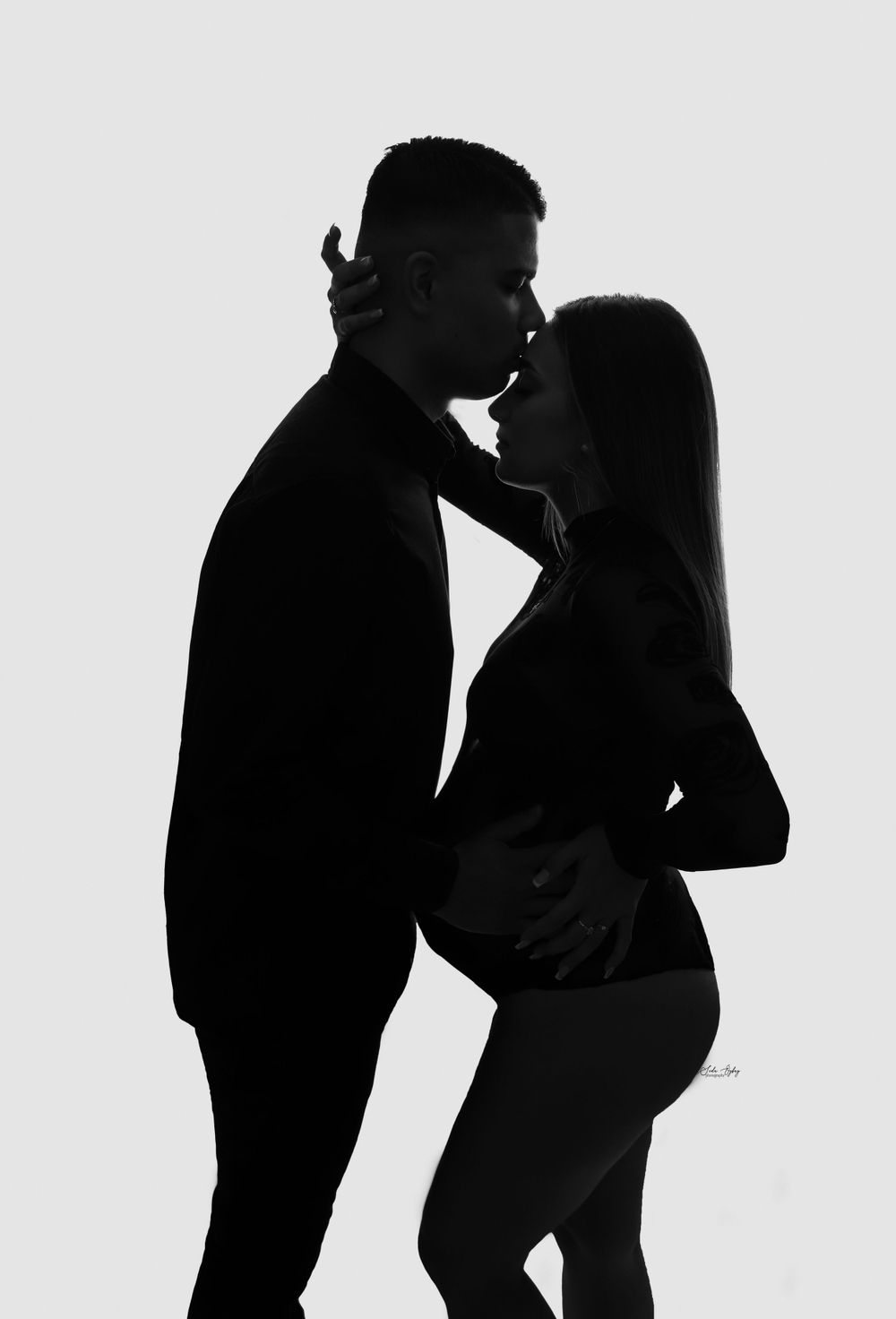 Artistic silhouette series of expectant couple showing tender moments against white background.