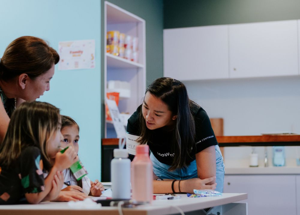 Students and teachers work together at desks in a bright classroom setting.