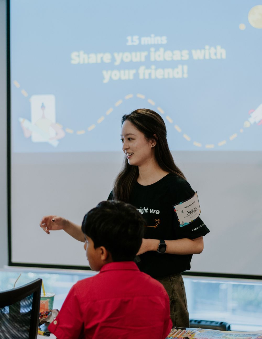 Students collaborate at a workshop with laptops and presentation screens in a modern learning environment.