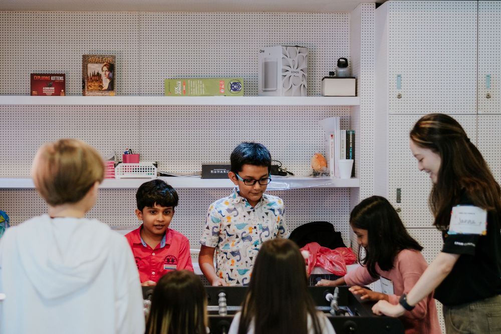 Students work together at tables in a classroom while engaging in collaborative learning activities.