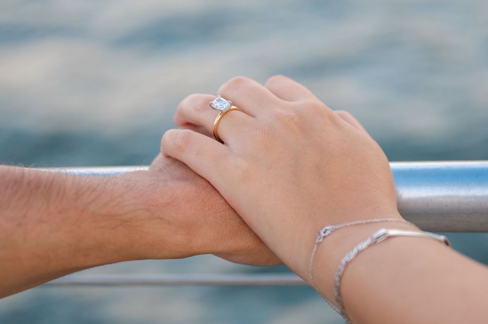 Close up shots of hands and engagement ring against waterfront railing.