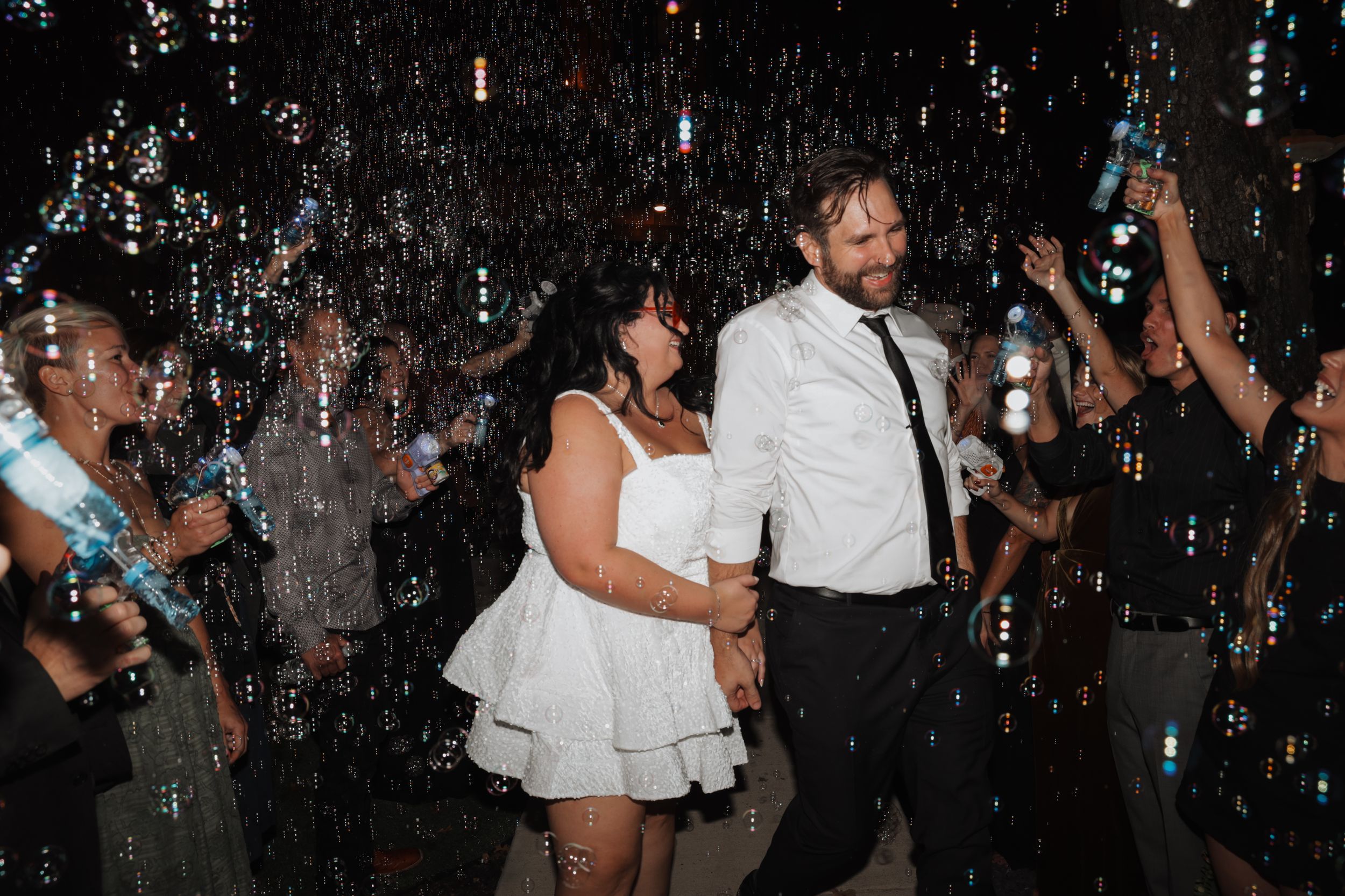 People dance and celebrate at a lively party with confetti falling from above in a dimly lit venue.
