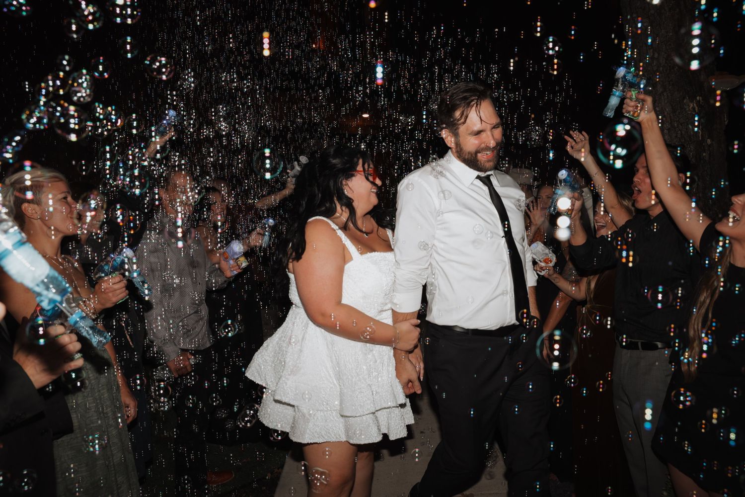 People dance and celebrate at a lively party with confetti falling from above in a dimly lit venue.