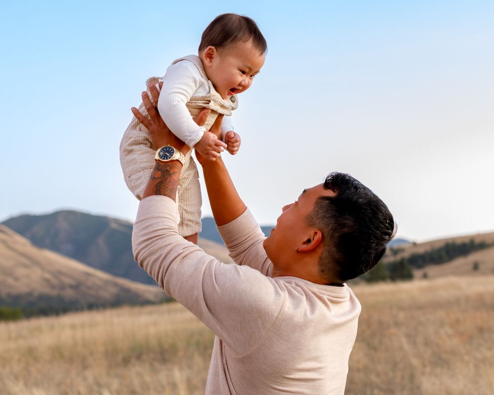 Father holds baby with Montana Mountains in background
