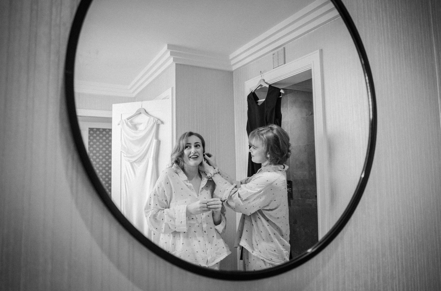 Three round mirrors on a gray wall reflect people getting ready for a special occasion.