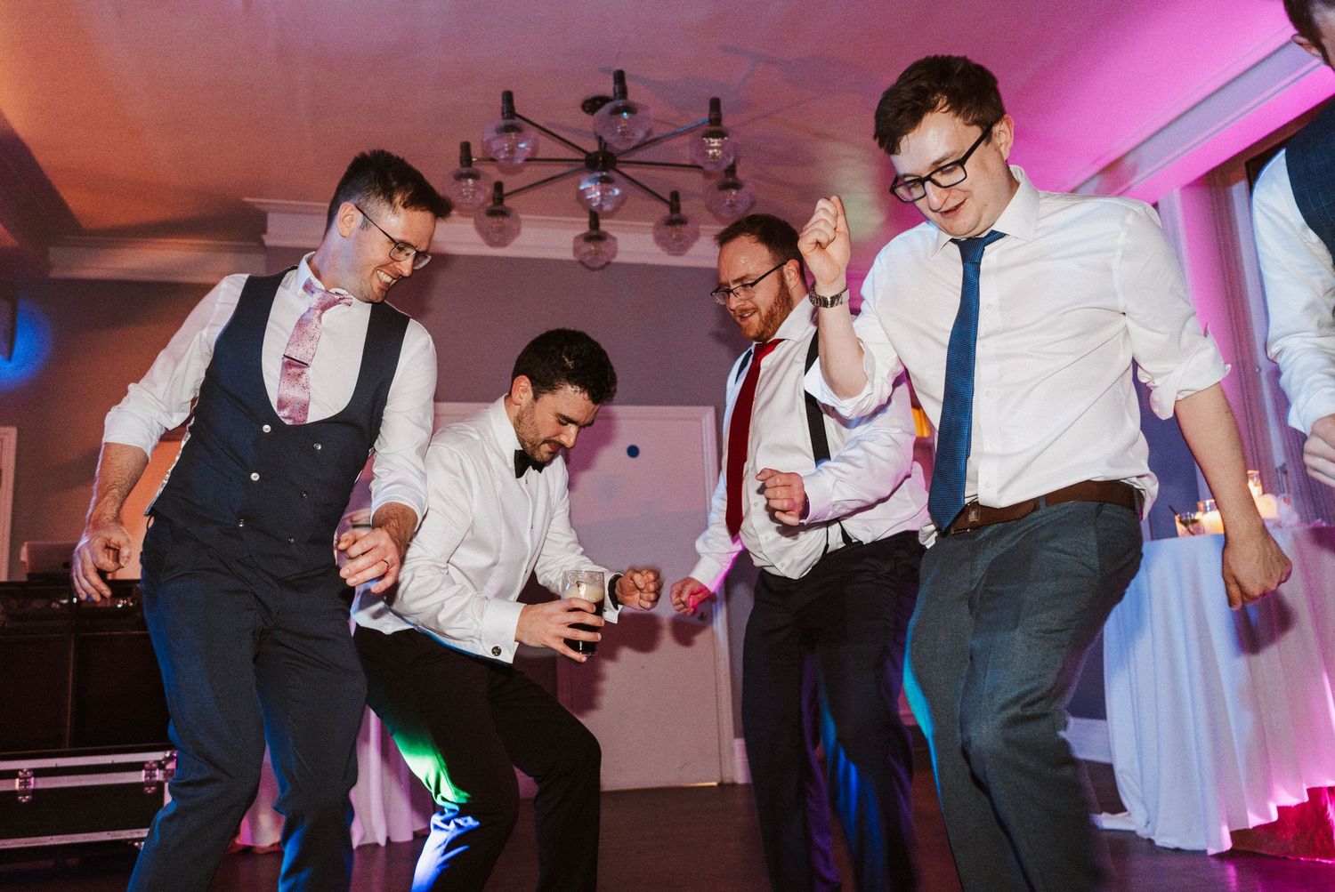 Wedding guests dancing and celebrating on a colorful illuminated dance floor at an evening reception.