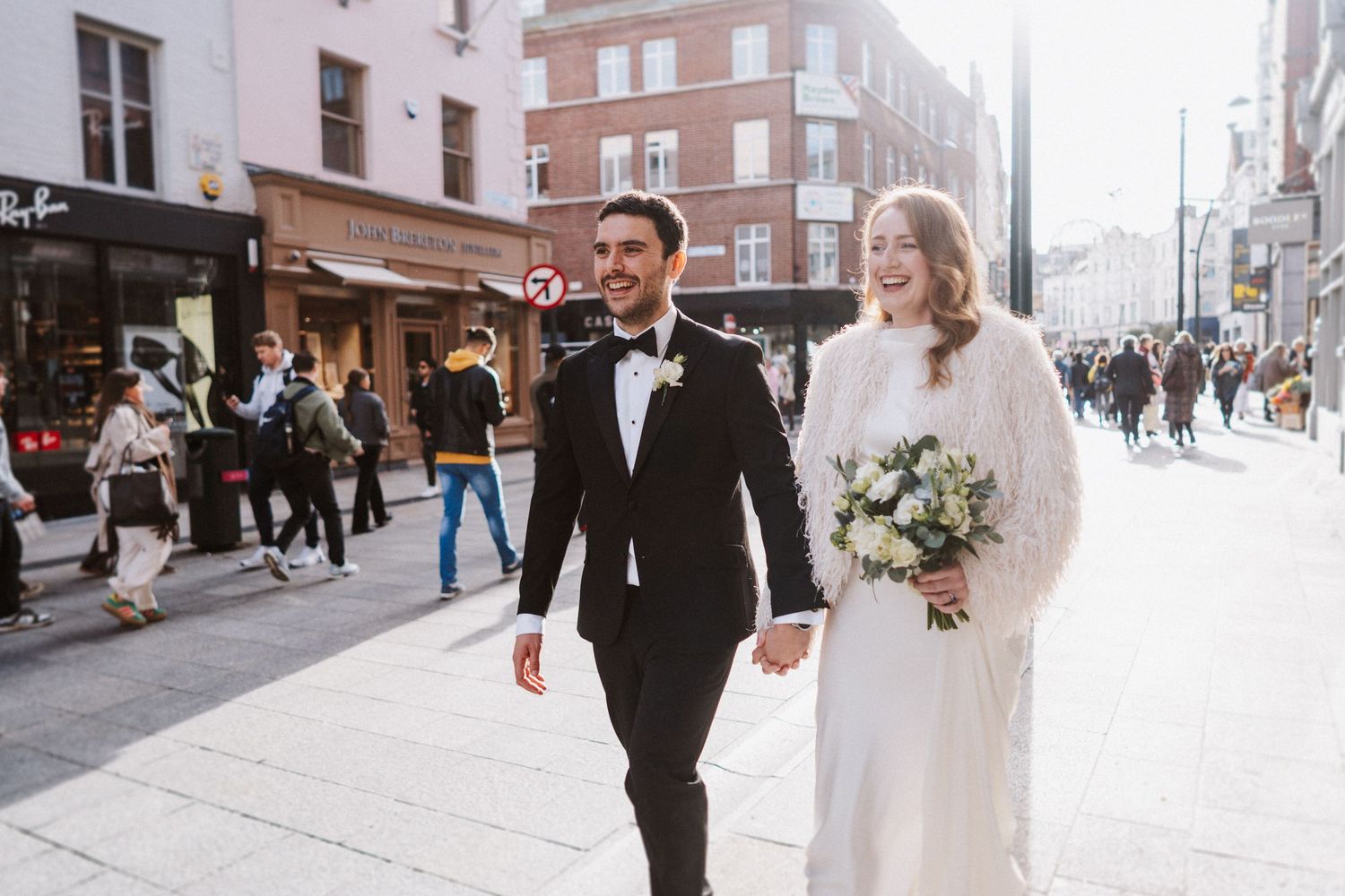 Couple walking together through city streets on their wedding day.