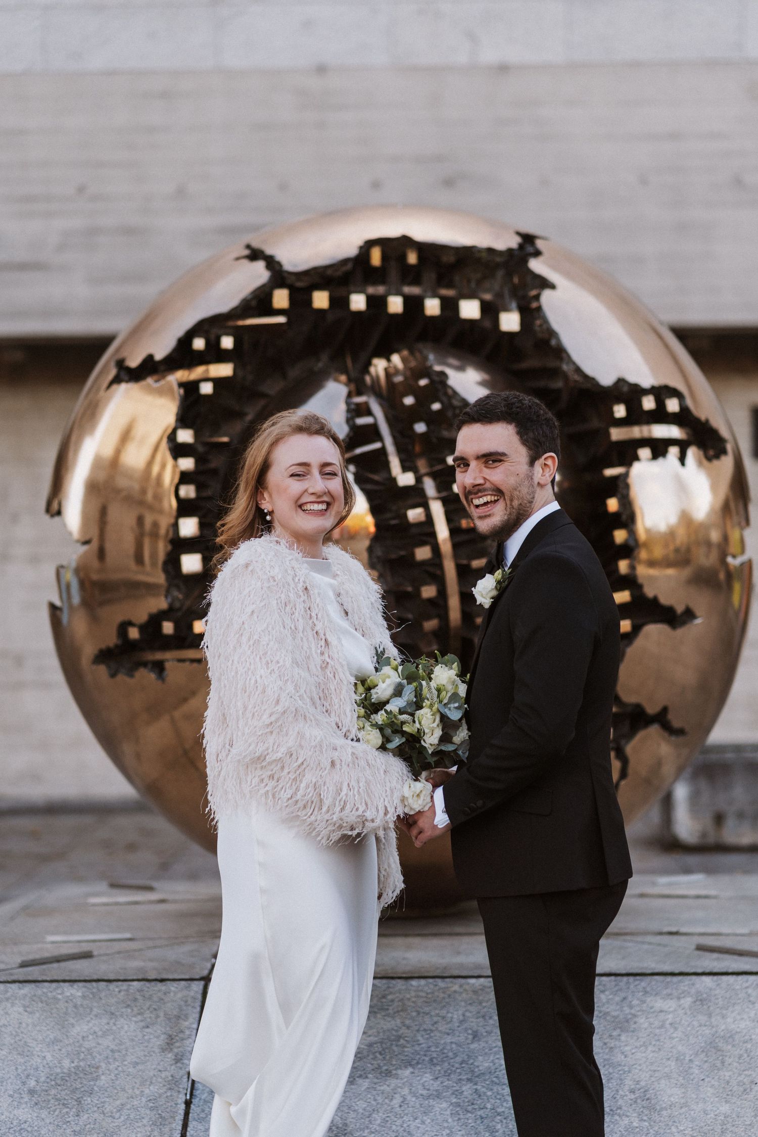 A couple shares a joyful moment together during their winter wedding celebration with decorative lights in the background.