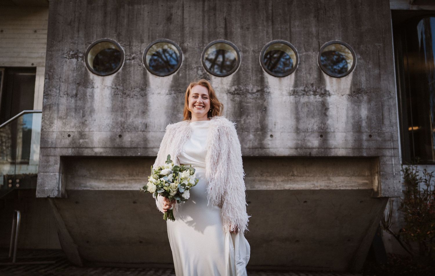 Modern industrial wedding venue with circular windows and concrete walls.