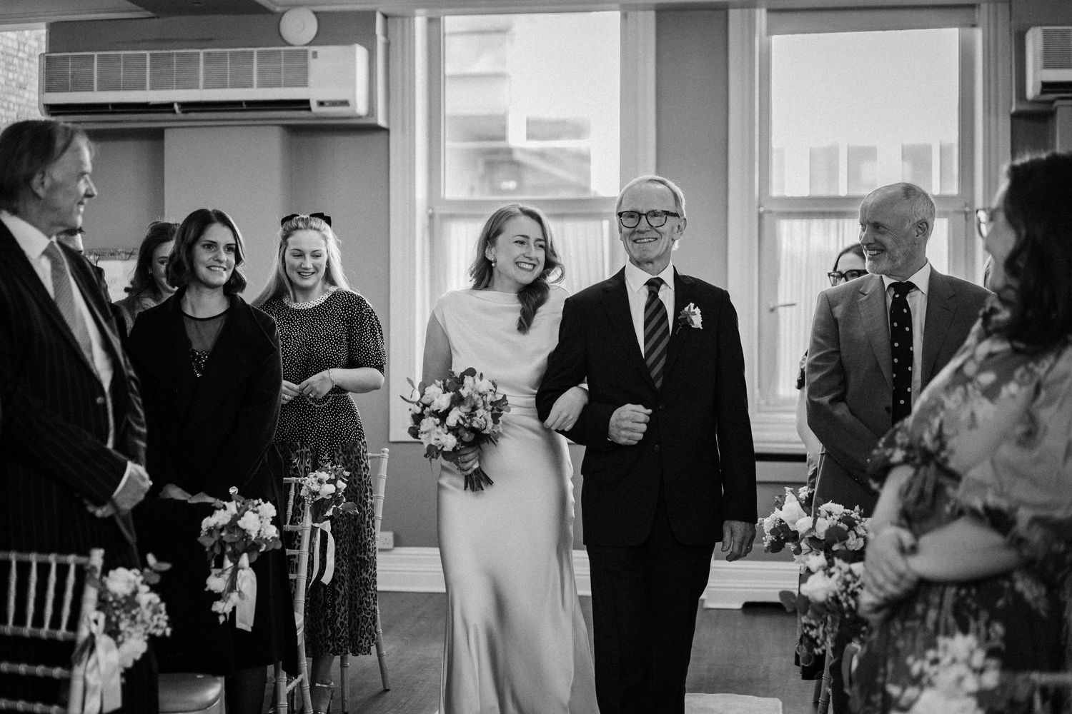 A series of black and white wedding photos showing candid moments and joyful celebrations during a ceremony.