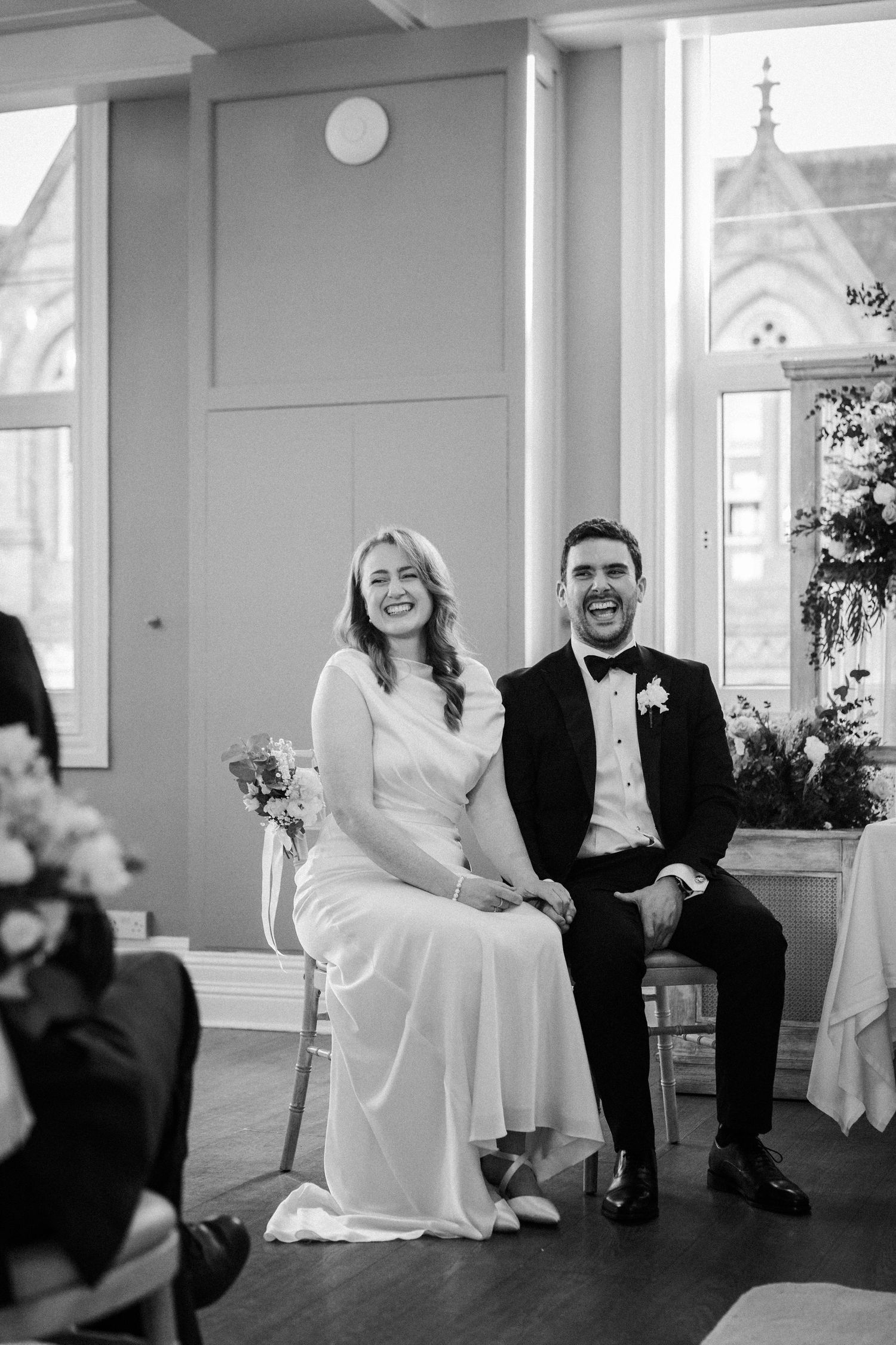 Black and white wedding photo series showing candid moments and laughter during an indoor celebration.