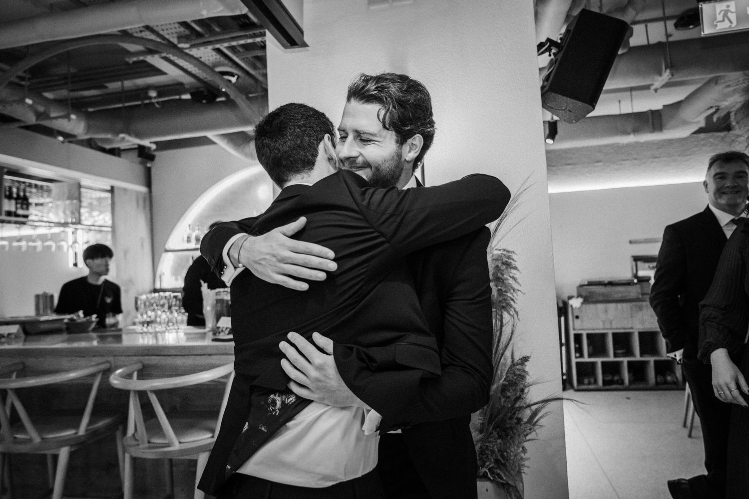 Black and white photos showing emotional embraces and celebrations at a wedding reception.