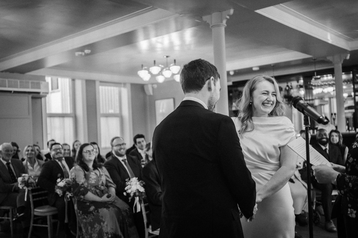 Wedding reception guests dance and celebrate in a dimly lit ballroom venue.