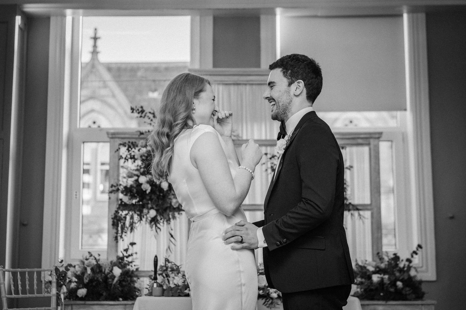 Elegant black and white wedding photos showing intimate moments between a couple in an indoor venue.