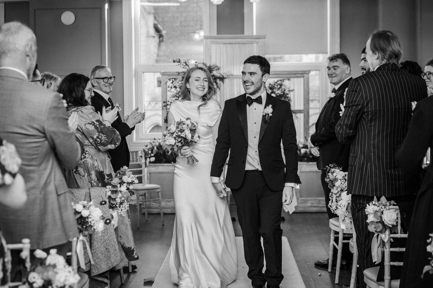 Black and white candid shots capture joyful dancing and celebration at an indoor wedding reception.