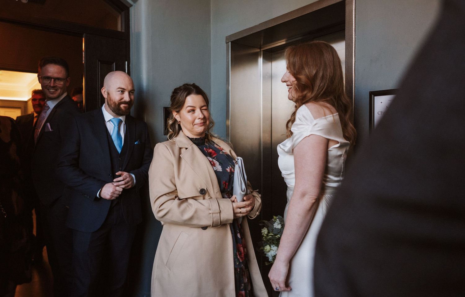 Wedding guests mingle and chat during an indoor reception celebration.
