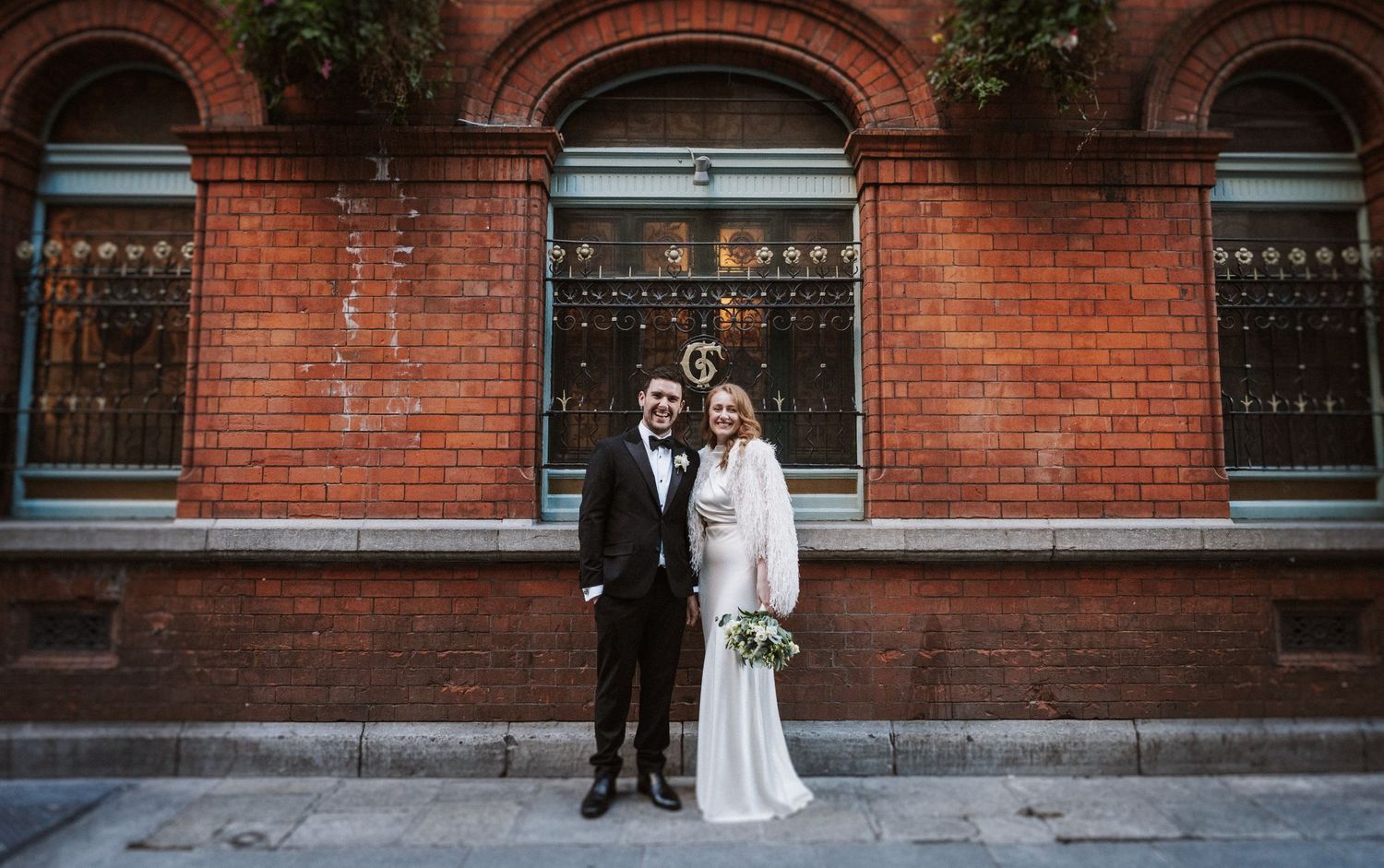 Wedding photography against classic red brick architecture showing full length portraits.