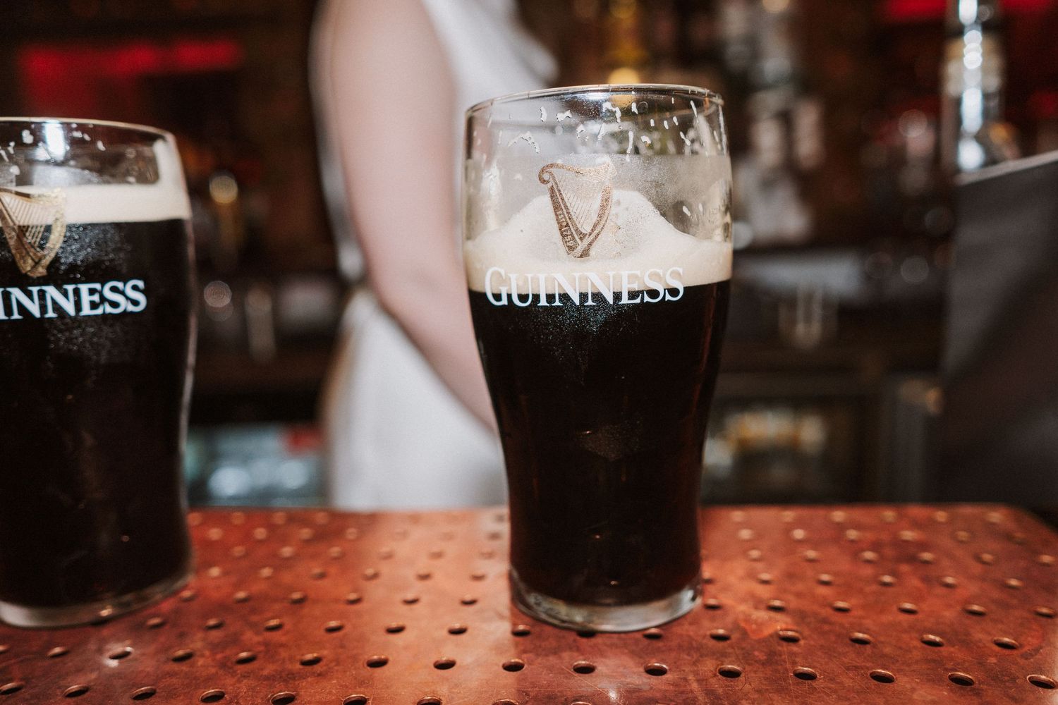 Row of Guinness pints lined up on a red textured bar counter.