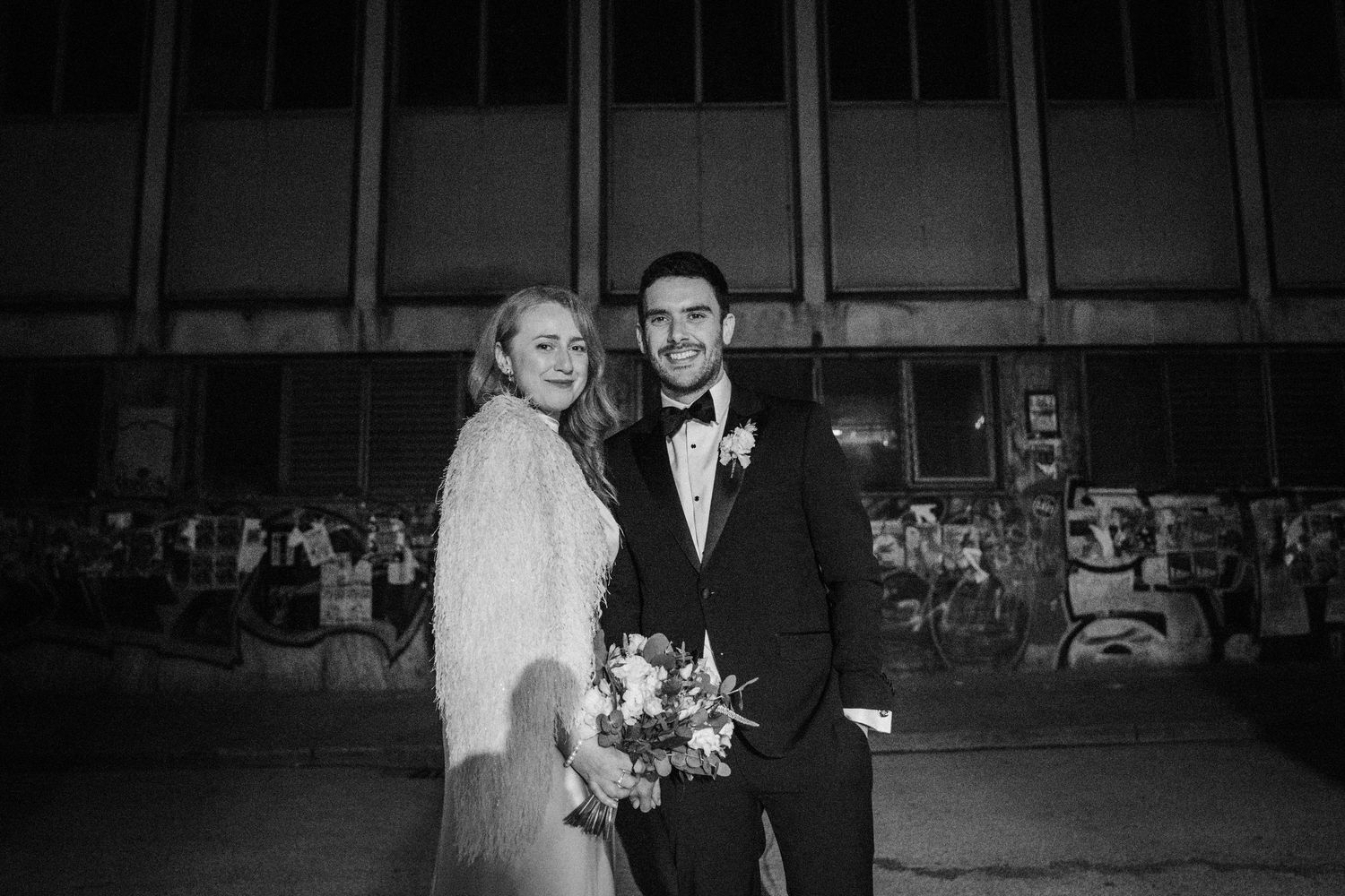 Monochrome wedding photos show guests mingling and celebrating in a dimly lit venue space.