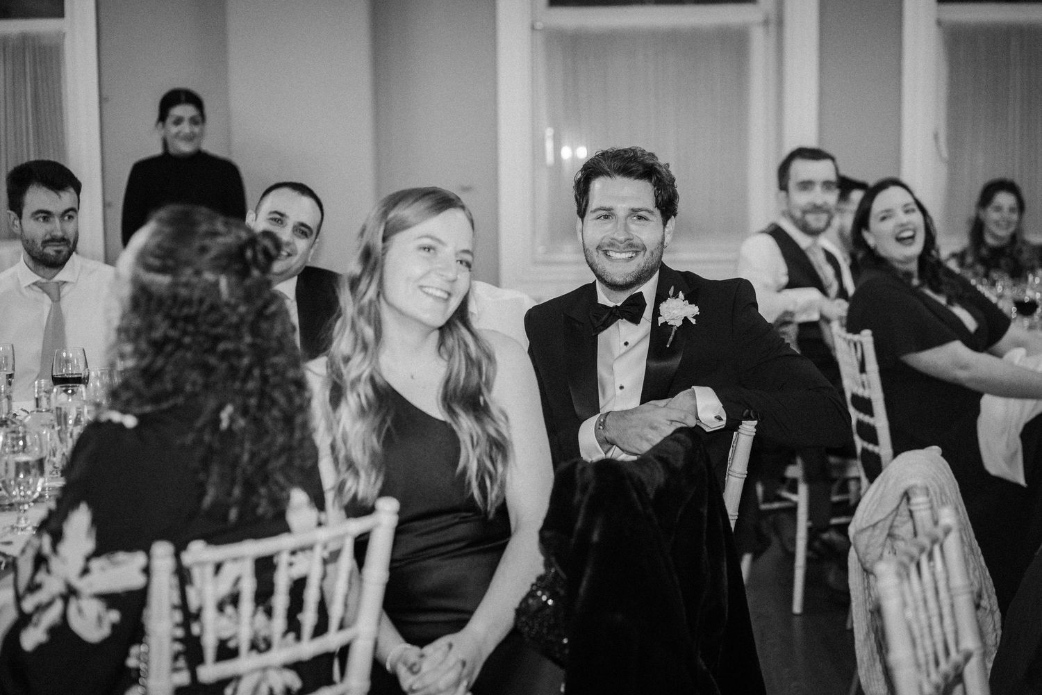 Black and white photo of wedding guests dancing and celebrating at a reception.
