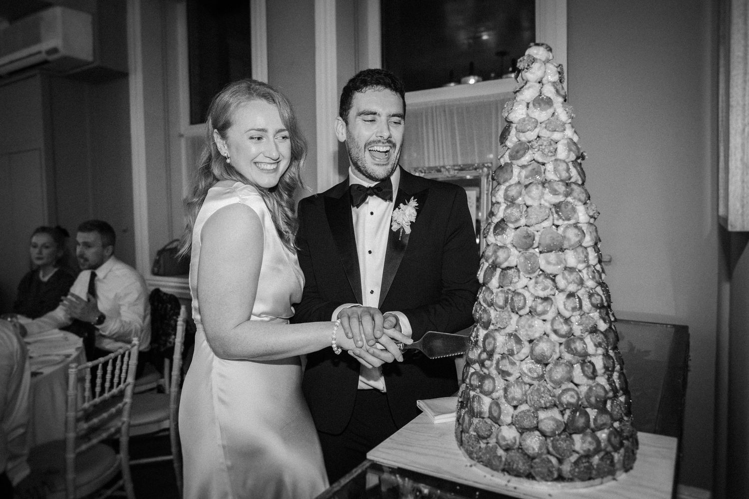 Black and white wedding reception photos showing guests dancing and celebrating with a multi-tiered cake.