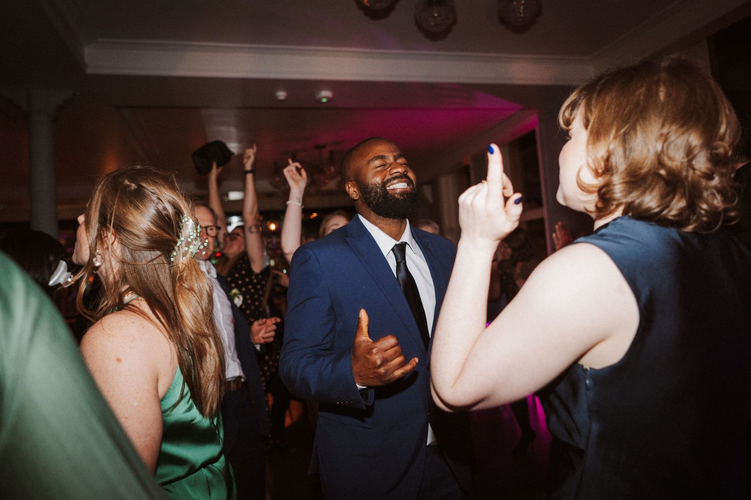 Partygoers dance and laugh together at an evening celebration with dramatic lighting effects.