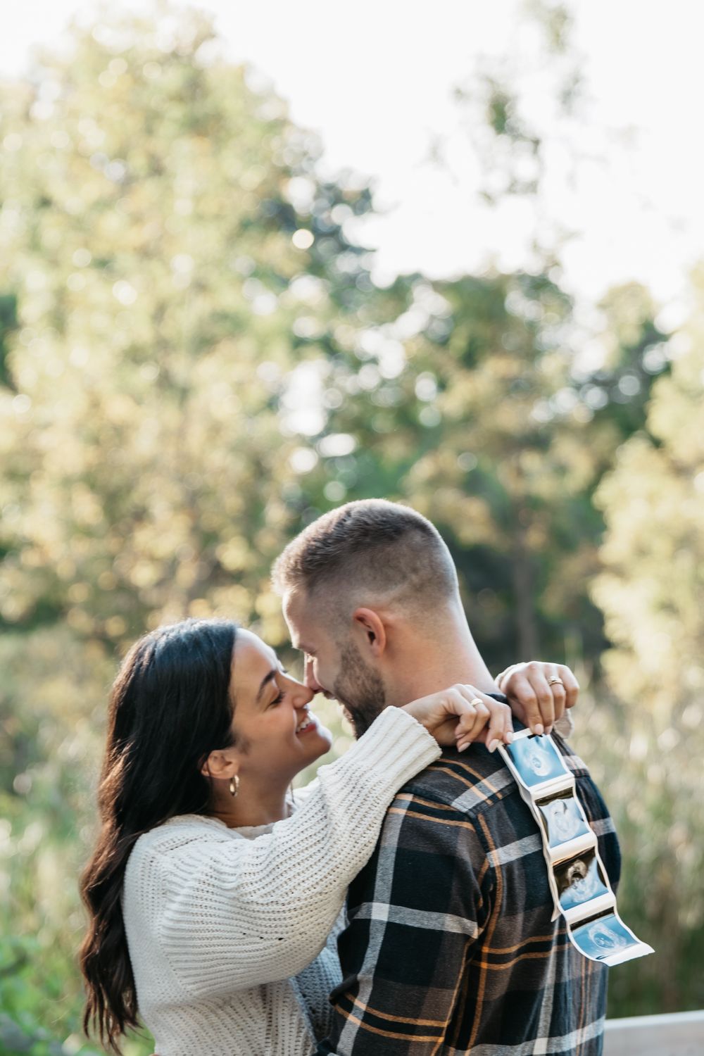 Couple sharing joyful moment while looking at ultrasound photos together outdoors in natural setting in Cuyahoga Falls, Ohio for photoshoot