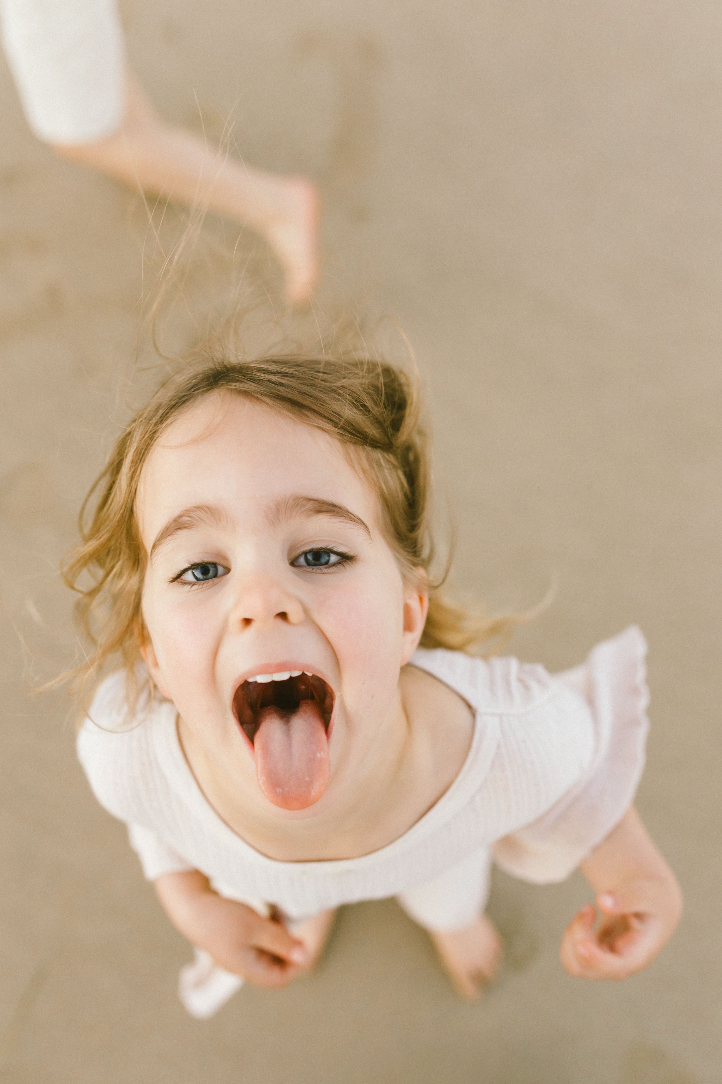 A series of playful expressions showing someone sticking out their tongue and making silly faces in white clothing.