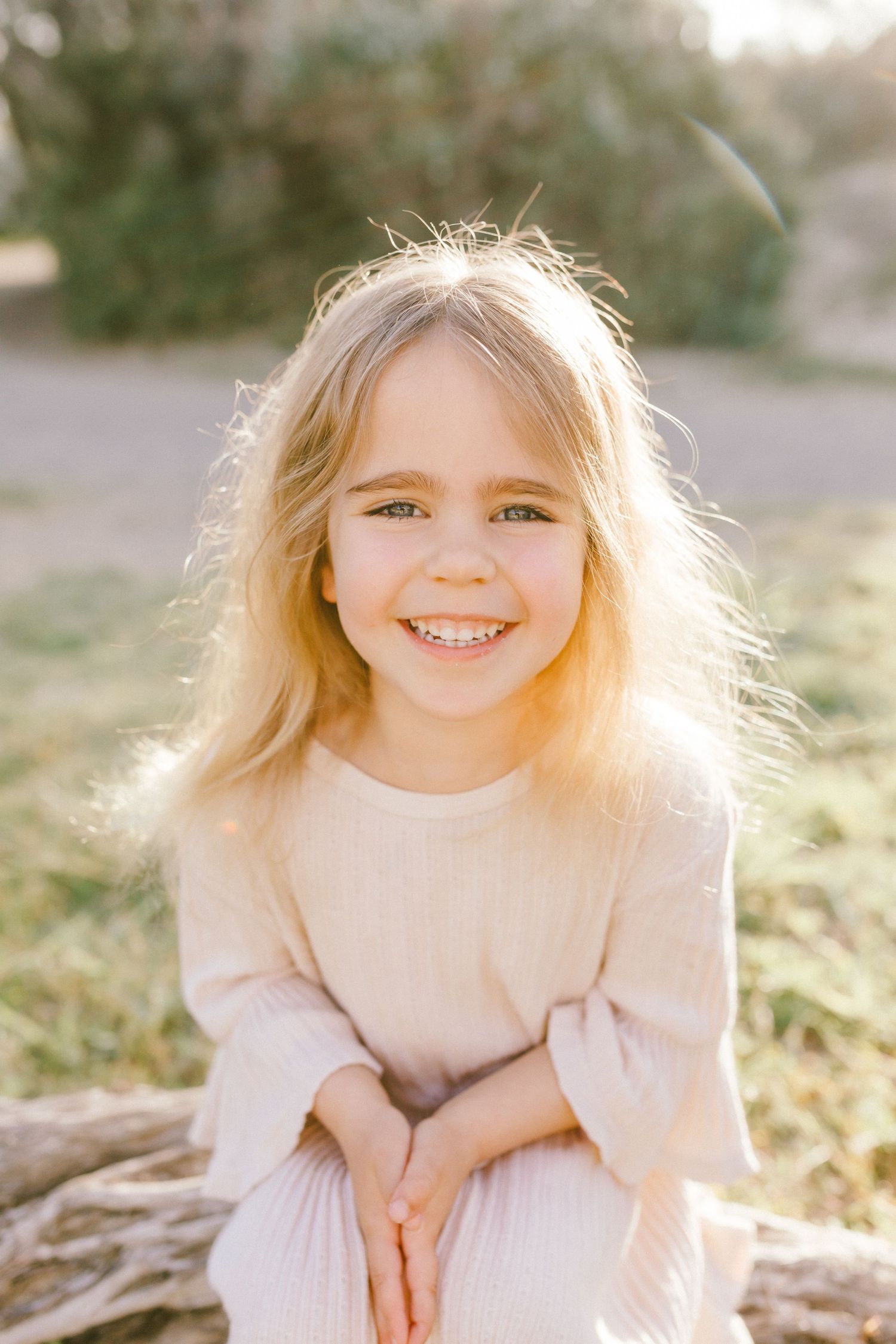 A series of four soft, sunlit outdoor portrait photographs showing joyful expressions against a natural background.