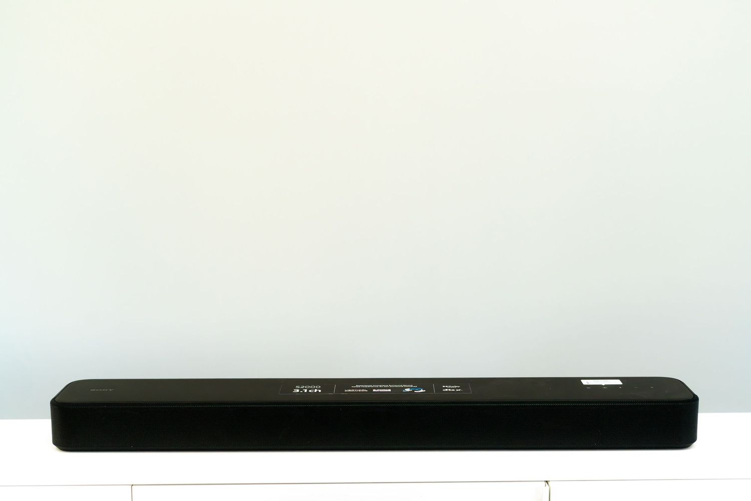 A sleek black soundbar sits on a white surface against a light background.