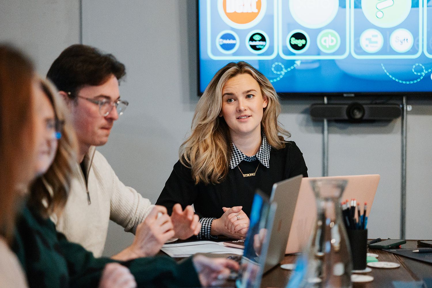 People sit at computer workstations in a modern office space with blue lighting visible in the background.