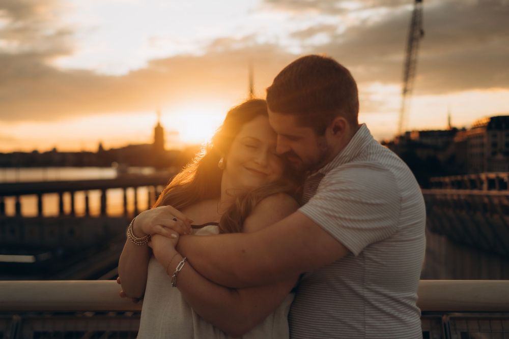 couple hugging in dramatic sunset light while being captured by Stockholm couple photographer in romantic couple photo shoot