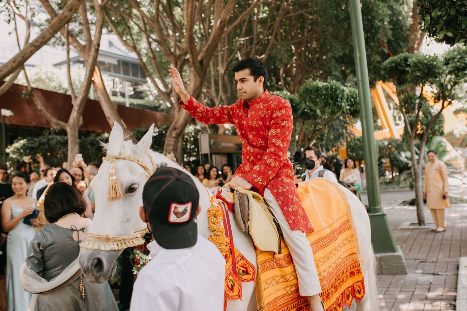 Outdoor wedding celebration with orange decorations and natural greenery.