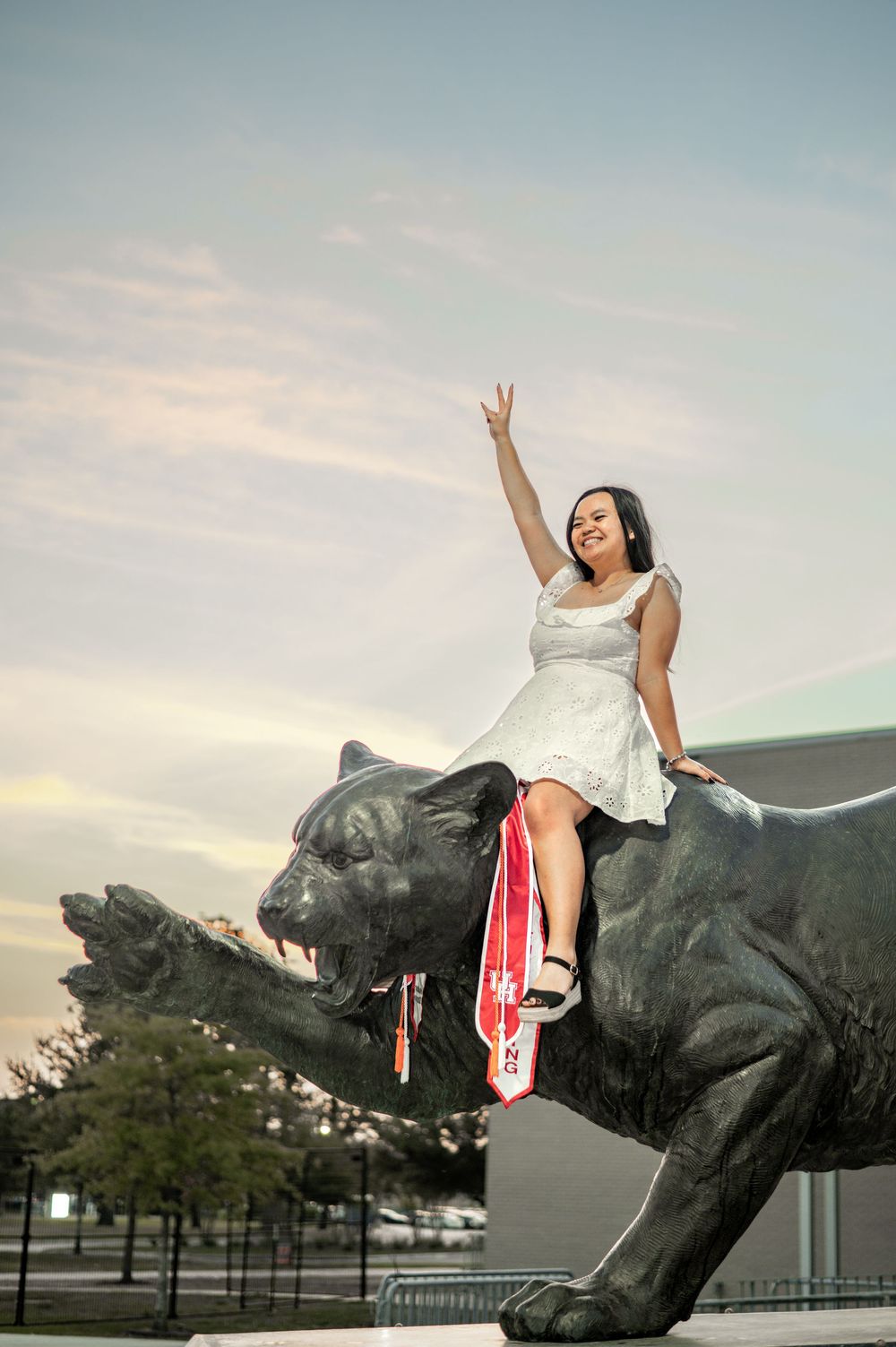 A sequence showing someone climbing and posing on a large black bull statue at sunset in an outdoor setting.