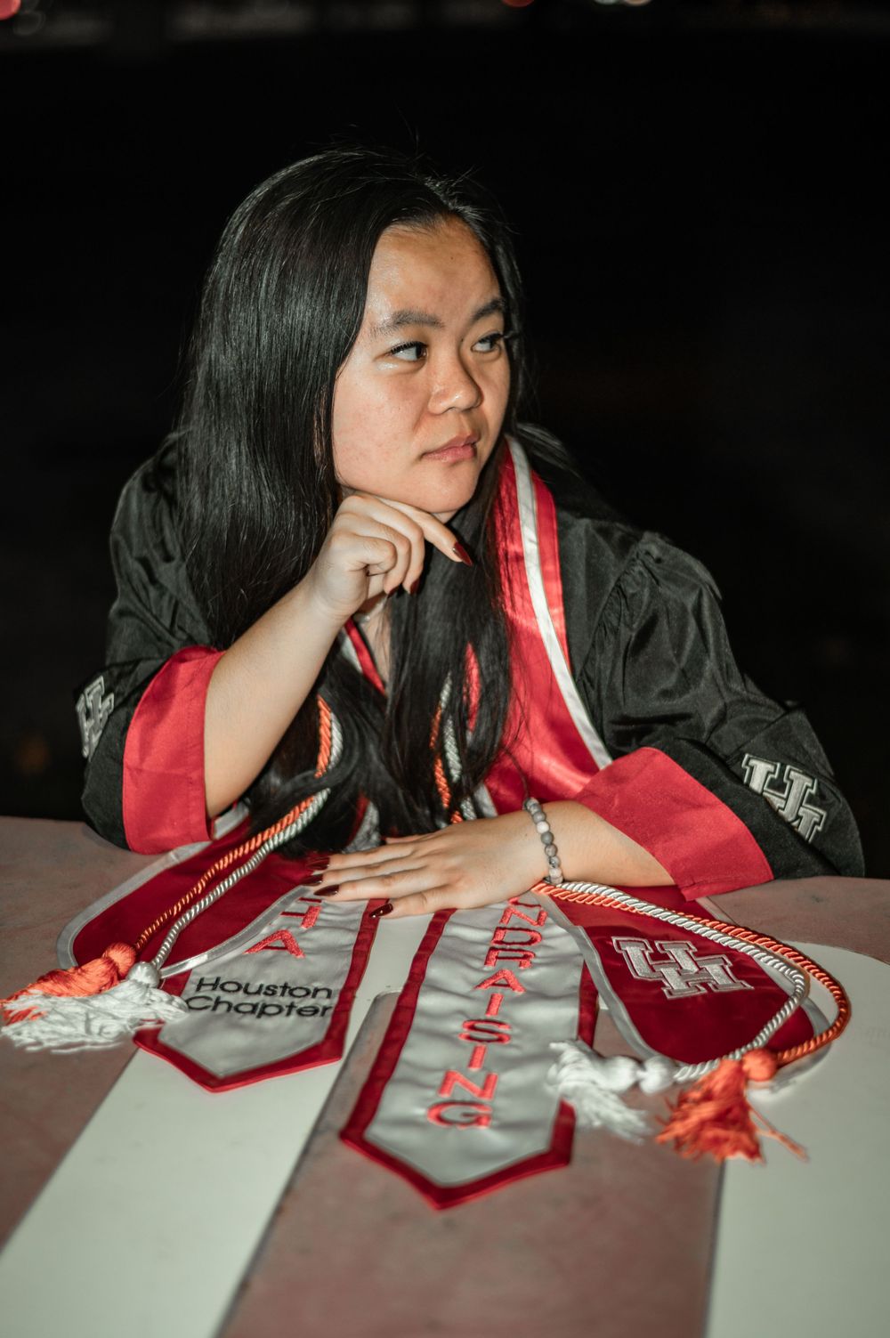 A person in dark clothing leans over a red and white banner laid out on a white surface in a dimly lit setting.
