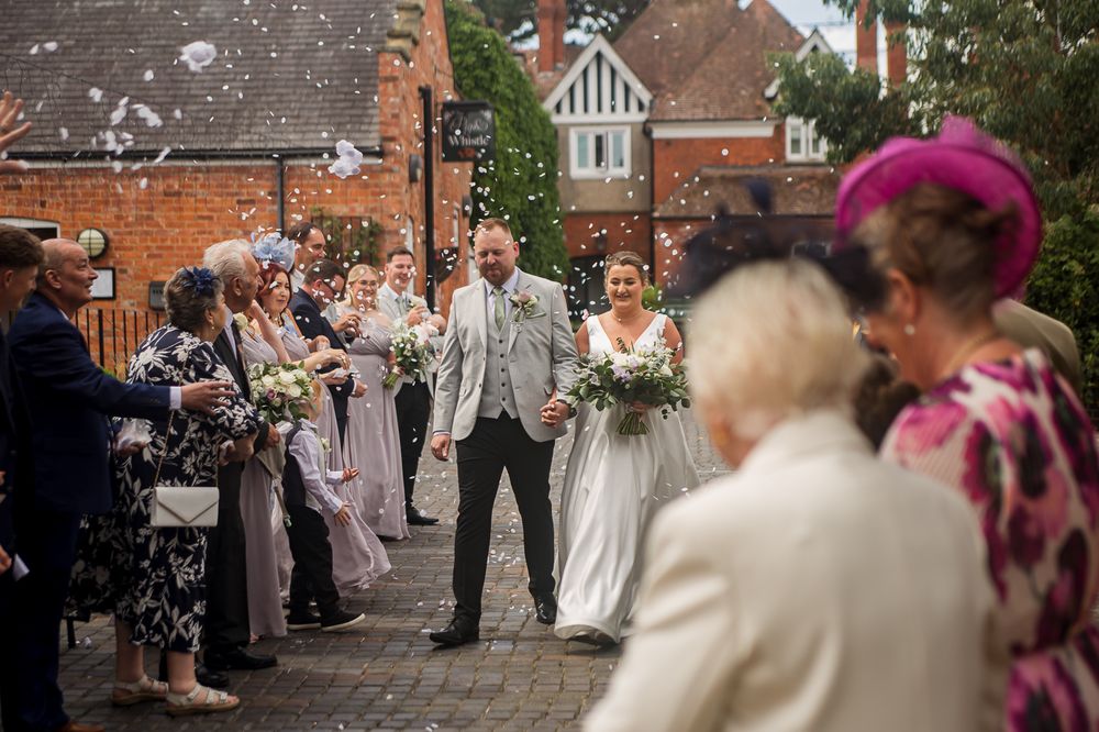 Wedding celebration on cobblestone courtyard with confetti being thrown in the air.