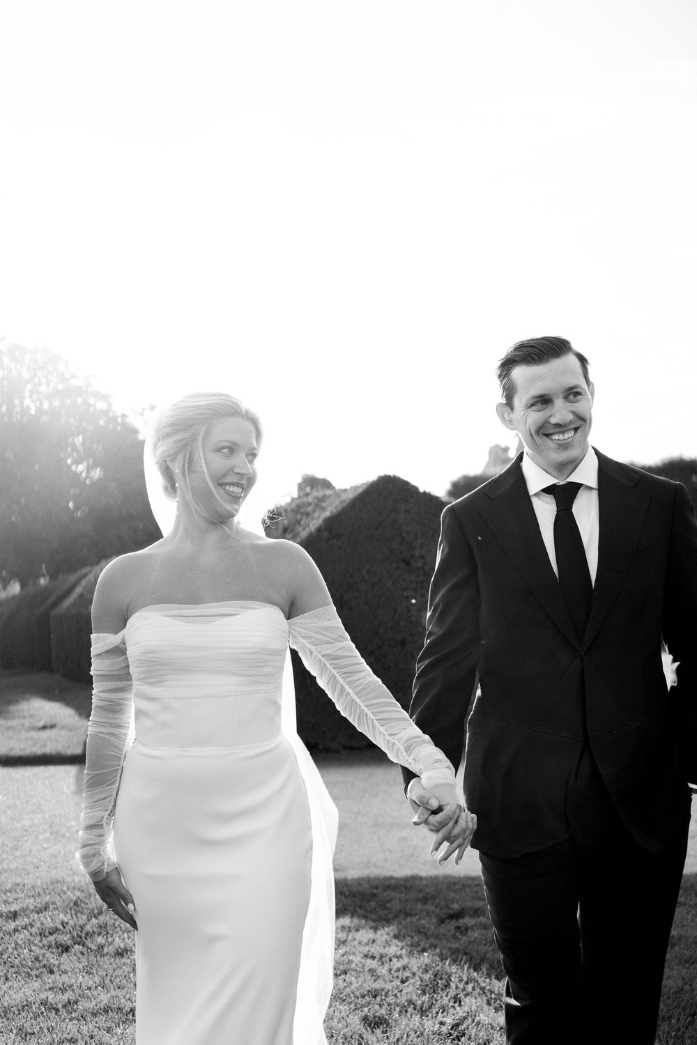 A series of joyful black and white wedding photos showing a couple laughing together in an outdoor field setting. Paris editorial elopement