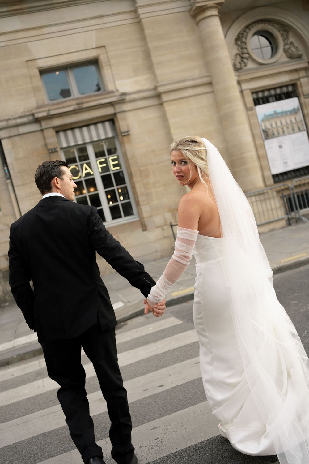 Sequence of a bride and groom walking together outside a historic building with cafe signage. Paris editorial elopement photographer.