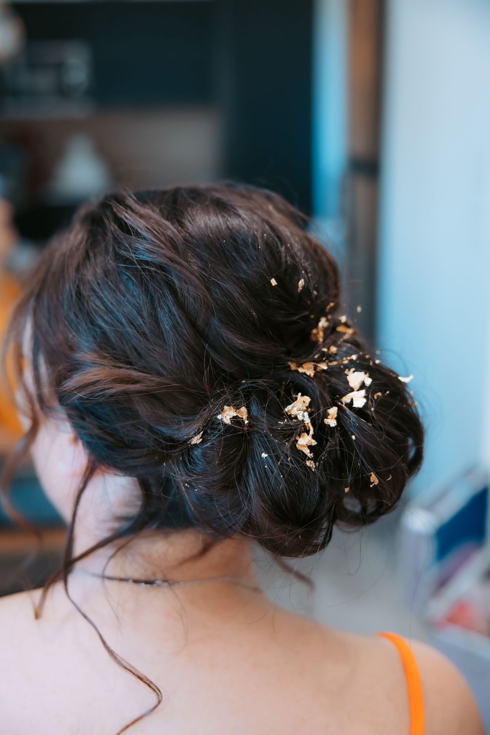 Elegant bridal hairstyle with delicate gold leaf accessories woven into dark updo.