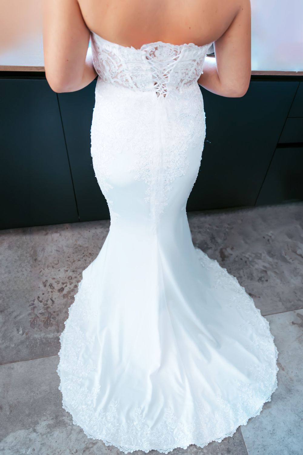 Full-length back view of fitted lace wedding gown with elegant train.