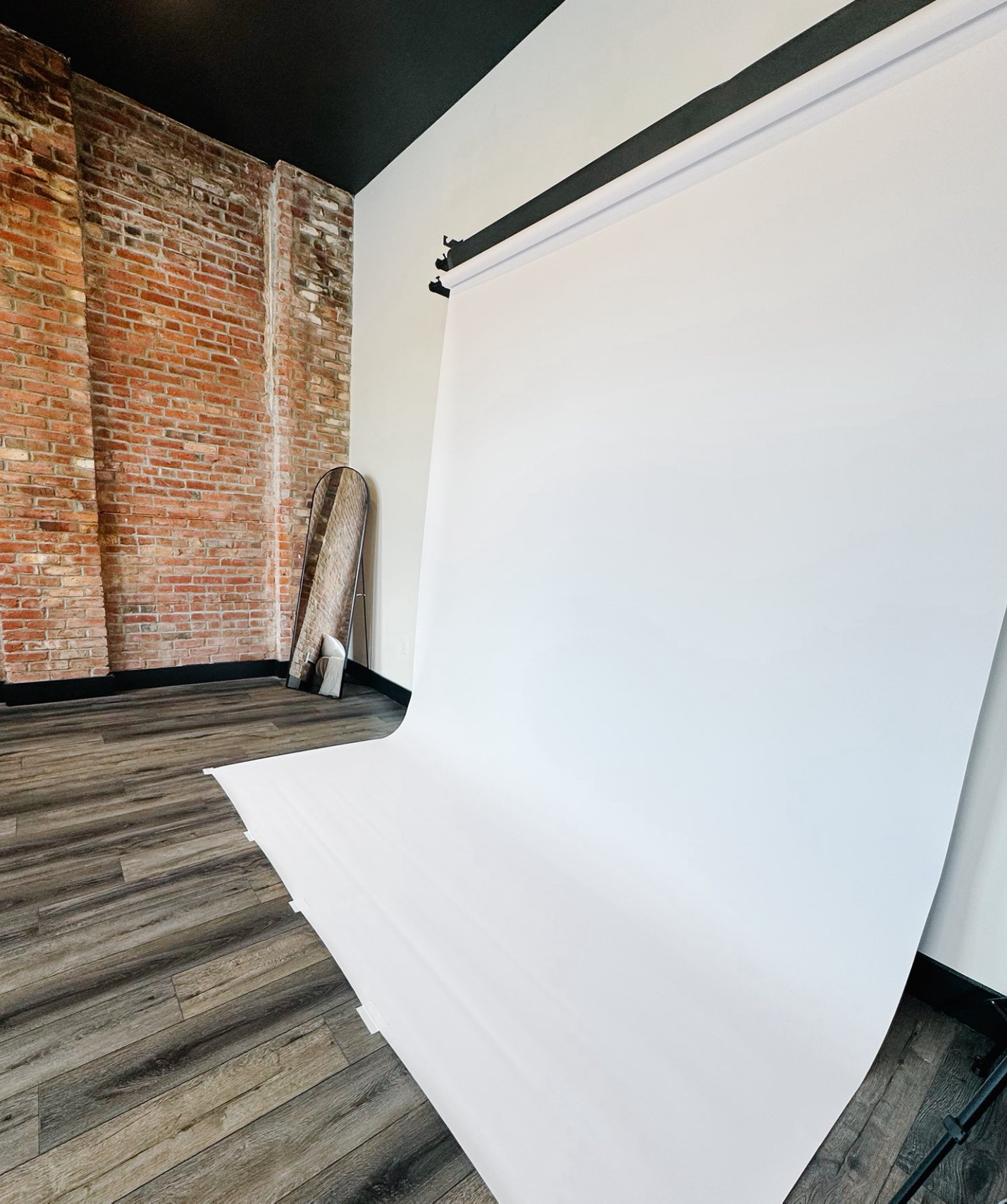 Modern interior space with exposed brick wall, white walls, and rustic gray wood flooring creates an industrial chic aesthetic.