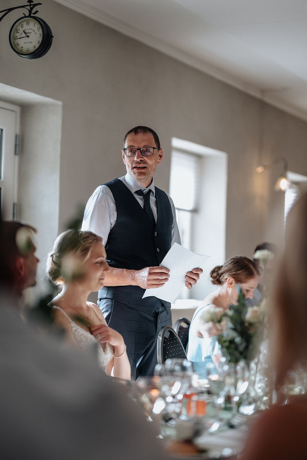 A formal dining reception setup with guests seated at tables while someone delivers a speech.